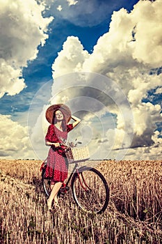 Girl with bicycle on wheat field.