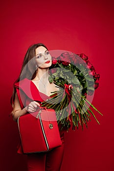 Girl with big bouquet of red roses on shoulder dreaming.