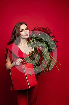 Girl with big bouquet of red roses on shoulder dreaming.