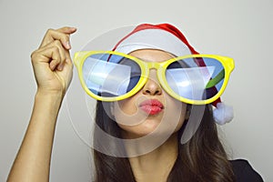 Girl with big funny sunglasses and Santa Claus hat celebrates Christmas