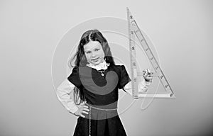 Girl with big ruler. School student study geometry. Kid school uniform hold ruler. School education concept. Learn