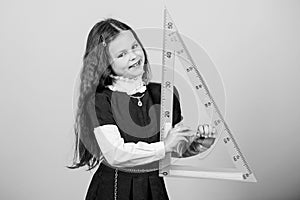 Girl with big ruler. School student study geometry. Sizing and measuring. Kid school uniform hold ruler. School