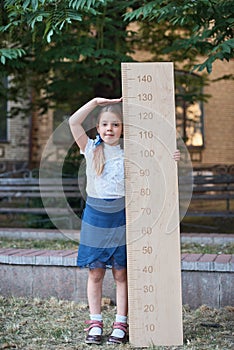 Girl with big ruler standing on park background. Farewell Bell. day of knowledge. beginning of the school year. education and scho