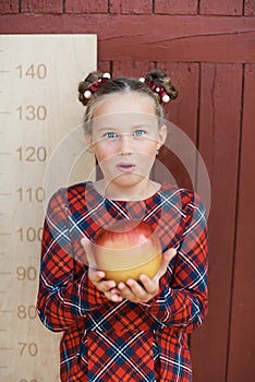 girl with big ruler standing on red wooden background. Farewell Bell. day of knowledge. beginning of the school year