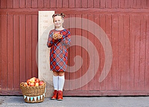 girl with big ruler standing on red wooden background. Farewell Bell. day of knowledge. beginning of the school year
