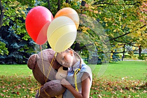 girl with big teddy bear and balloons in the park.  Problems teenagers at school