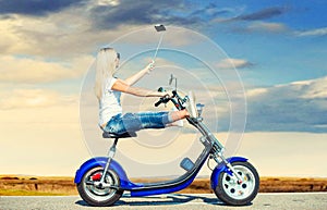 Girl biker riding a motorbike on an asphalt road and photographed.