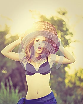 Girl in bikini and hat on the beach. Surprise.