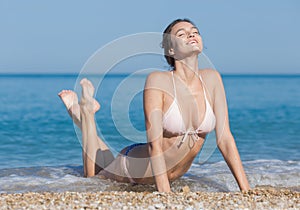 Girl in bikini lying bent back with eyes closed outdoors