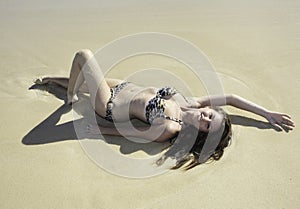 Girl in bikini lying on a sandy beach