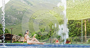 Girl in bikini reading a book by the pool