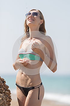 Girl in bikini and sunglasses poses under flowing water