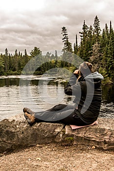 Girl with binocular sitting near Lake of two rivers in Algonquin National Park Canada Ontario natural pinetree landscape