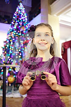 Girl with binocular stands near christmas tree in