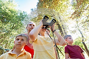 Girl with binoculars. Mom with children looks ahead