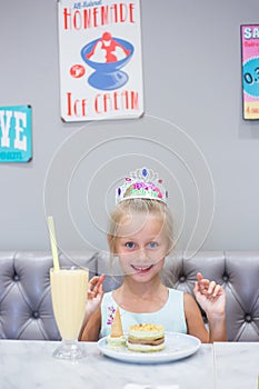 The girl at a birthday party. Joyful cheerful girl celebrates. Cocktail and cake on the table