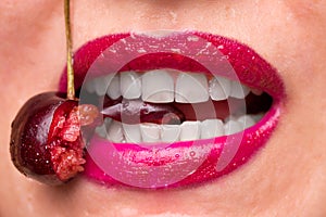 The girl bites a ripe cherry