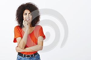 Girl biting nails from nervousness. Portrait of anxious insecure attractive female with afro hairstyle, holding finger photo