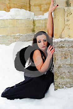 Girl with black angel wings in a black dress in winter