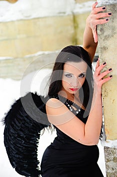 Girl with black angel wings in a black dress in winter