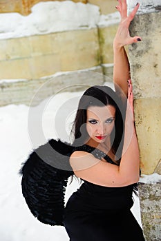 Girl with black angel wings in a black dress in winter