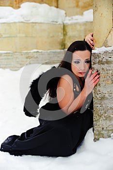 Girl with black angel wings in a black dress in winter