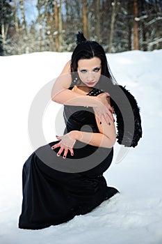 Girl with black angel wings in a black dress in winter