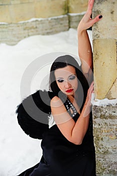 Girl with black angel wings in a black dress in winter