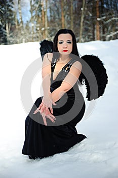 Girl with black angel wings in a black dress in winter