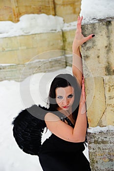 Girl with black angel wings in a black dress in winter