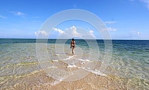 Girl in black bikini walking on the white beach