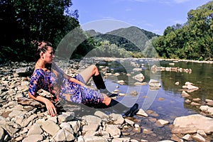 A girl in black boots is resting in nature.