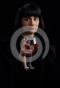 A girl in a black cape with a glass of red wine