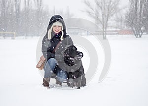 The girl with a black dog on the snowfield