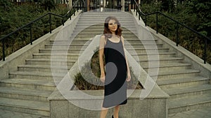 Girl in a black dress on the background of the stairs