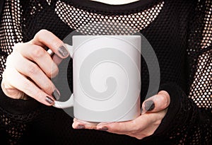 Girl in black dress is holding white mug. Mockup for Halloween gifts design.