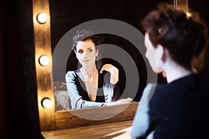 Girl in black dress looking in the mirror