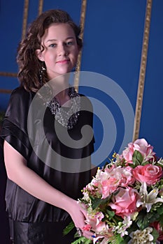 Girl in a black dress next to a vase with flowers