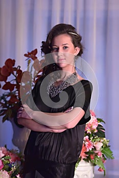 Girl in a black dress next to a vase with flowers