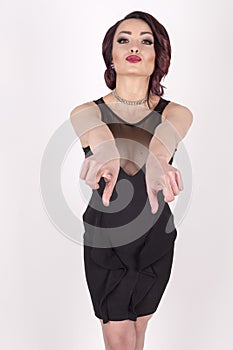 A girl in an black dress pointing forwards