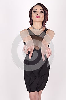 A girl in an black dress pointing forwards photo