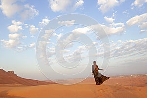 Girl in black dress standing in desert of Sharjah, United Arab Emirates.. back view