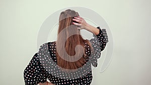 Girl in a black dress with white circles goes back and straightens her hair