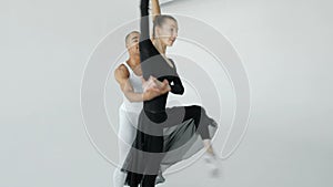 Girl in black and a guy in white dancers rehearse performance in a ballet school near a large window close-up 20s 4k