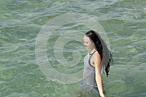 A Girl with black hair walking through the ocean