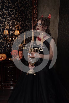 Girl in black Halloween dress in devil costume with red horns