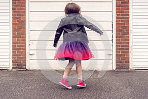 Girl in a black leather jacket dancing outside