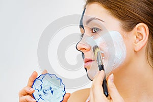 Girl black mask on half face apply white mud