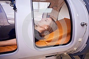 A girl in a black T-shirt lies in a hyperbaric chamber, oxygen therapy