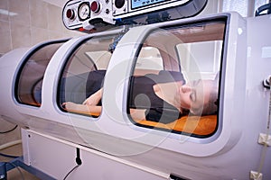 A girl in a black T-shirt lies in a hyperbaric chamber, oxygen therapy